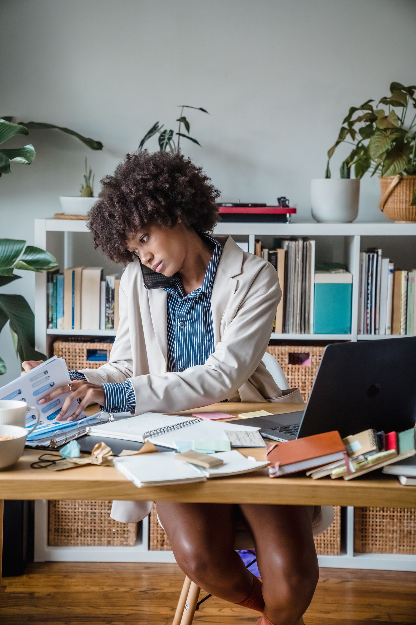 Stock photo of a woman speaking on the phone while reviewing documents at a desk