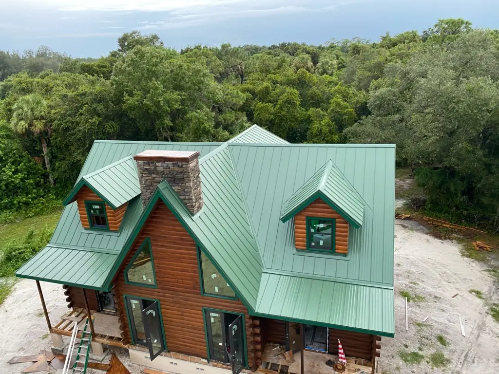Green standing-seam metal roof on a log-style home under construction