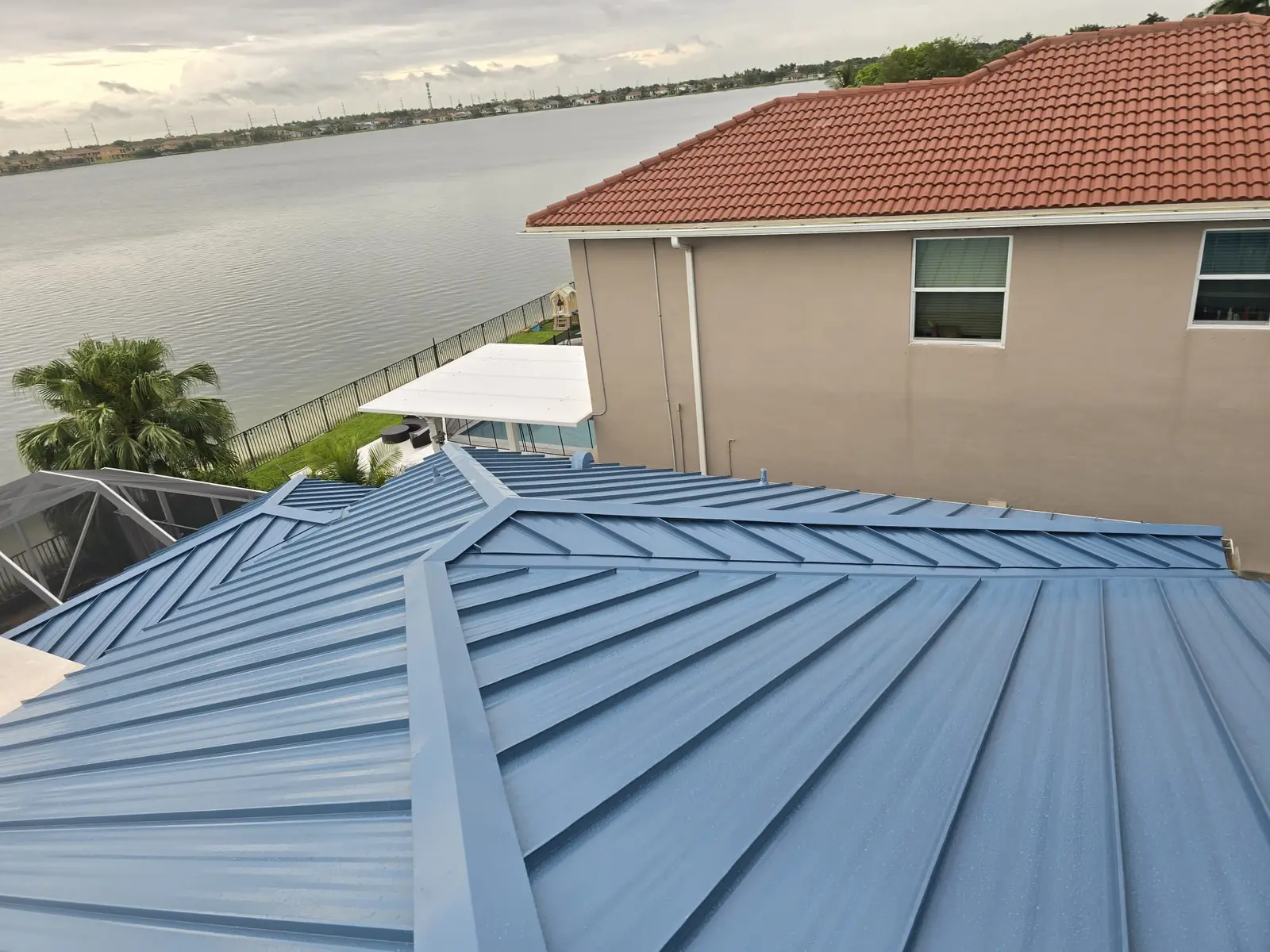 Completed Regal Blue mechanically seamed standing-seam metal roof beside a lake in Miramar.