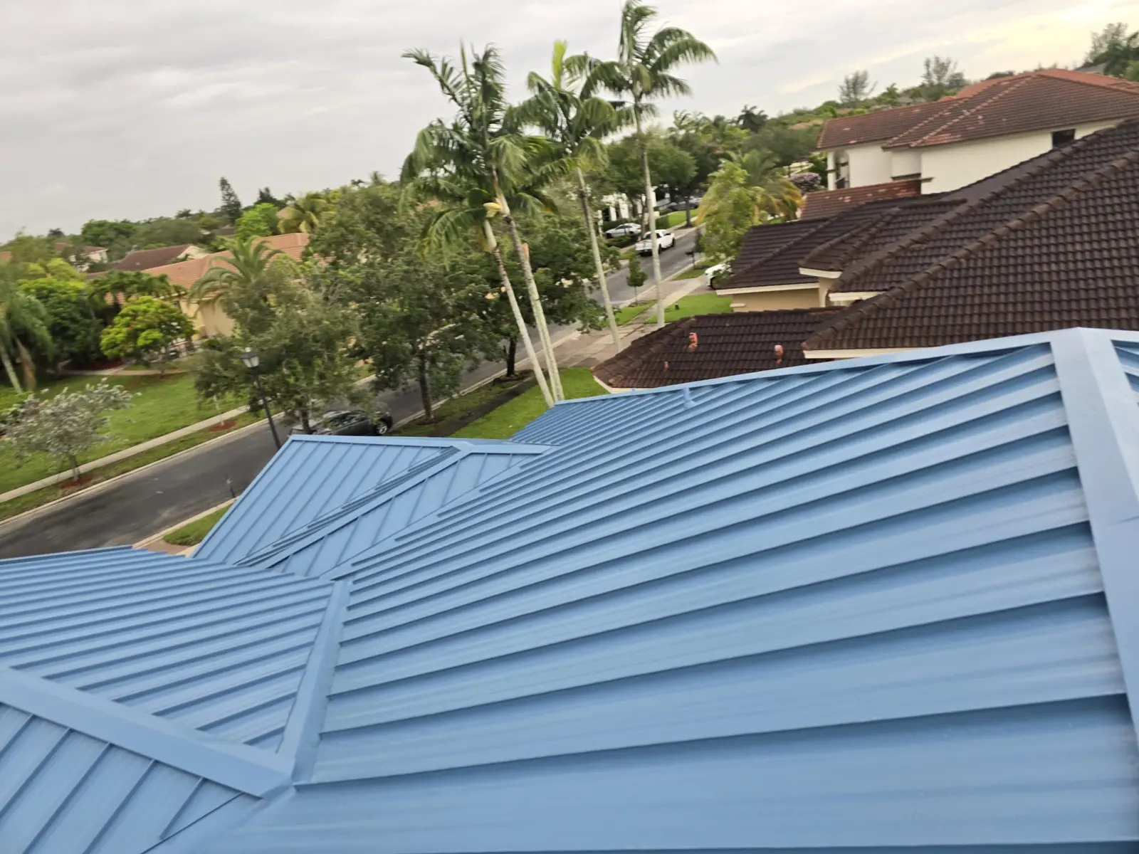Completed Regal Blue standing-seam metal roof across finished hips and valleys in Miramar, Florida.