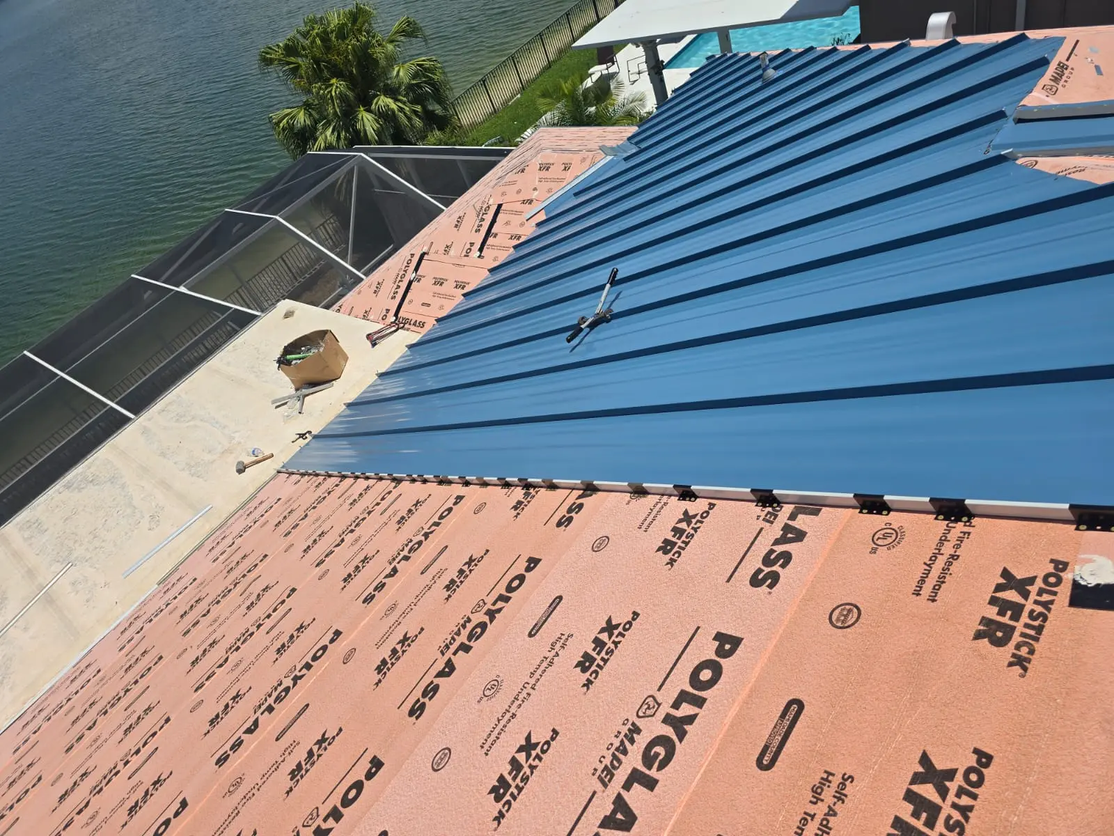 Regal Blue standing-seam panels being installed over Polystick XFR underlayment on a Miramar roof.
