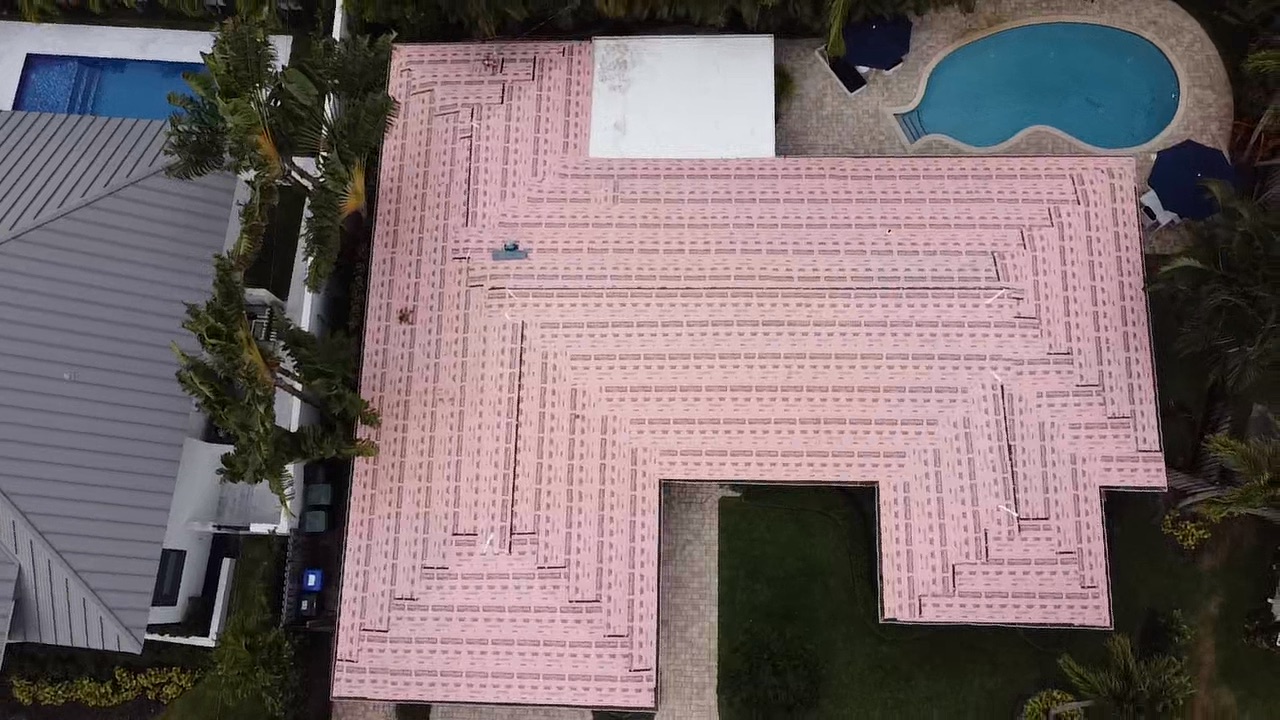 Aerial view of pink Polystick XFR underlayment covering a South Florida roof deck before metal panels are installed.