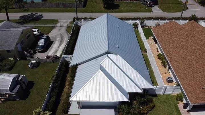 Aerial view of a light-colored metal roof with intersecting gable sections.