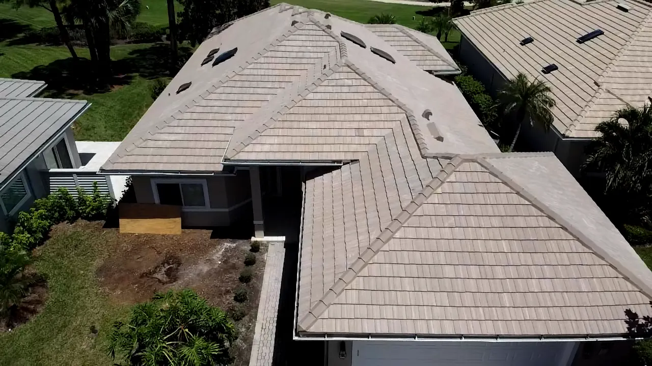 Oblique aerial view of a beige tile roof with multiple hips and roof sections.