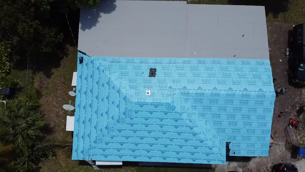 Top-down aerial view of blue roofing underlayment during a residential installation.