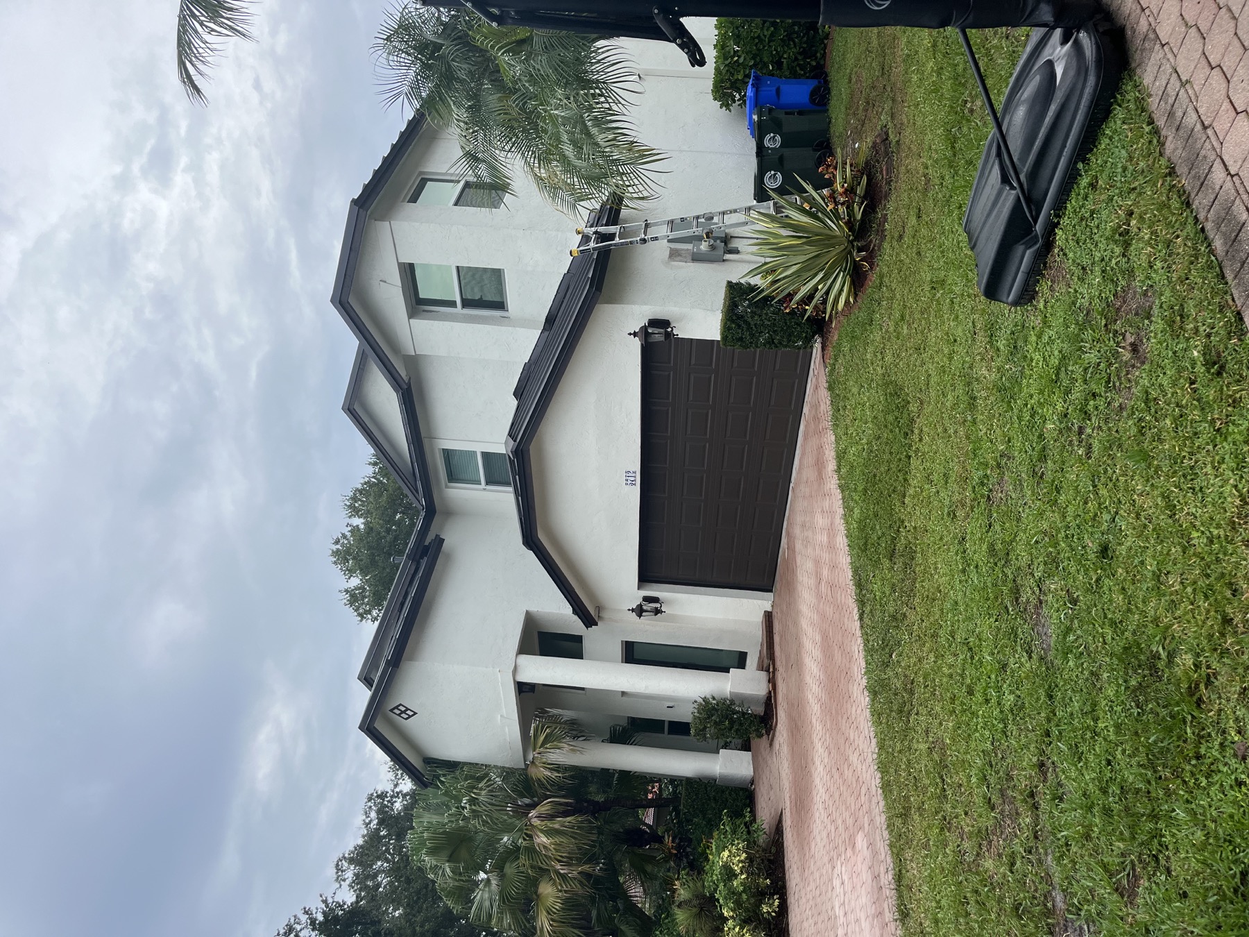 Completed Dark Bronze standing seam roof on a two-story white home in Coconut Creek