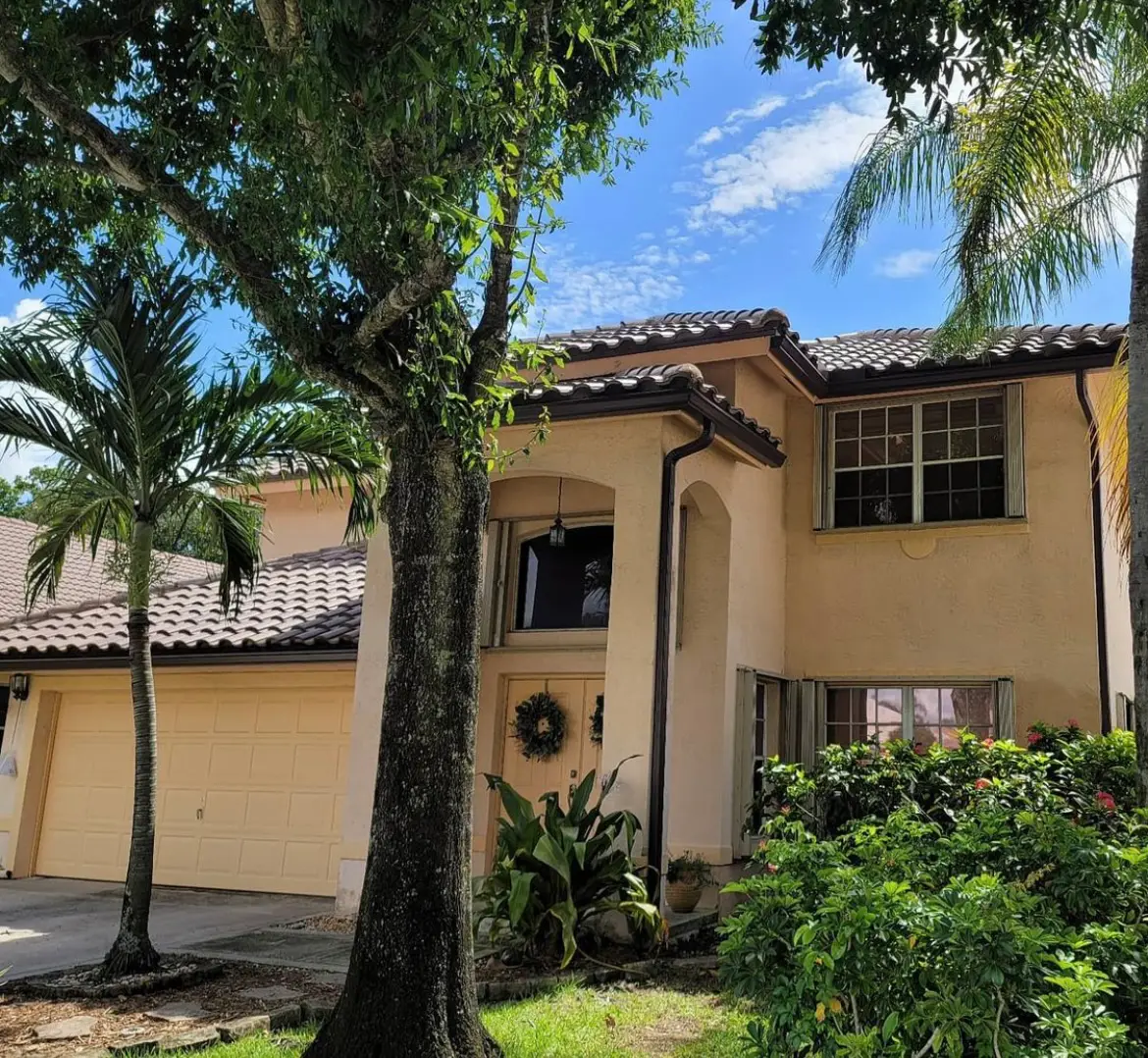 Dark concrete tile roof on a two-story stucco home surrounded by mature trees.