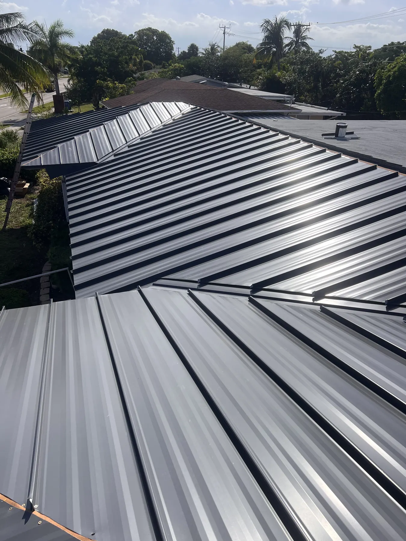 Close view of dark standing-seam metal panels meeting across a roof valley.