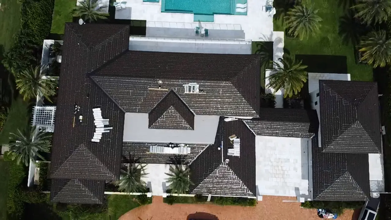 Aerial view of a dark tile roof while one roof section is being replaced.