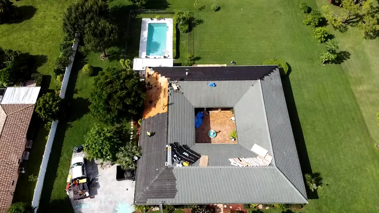 Aerial view of a gray metal reroof while panels and roof decking are being installed.