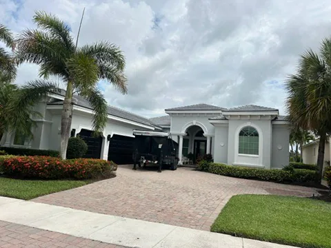 Street view of a single-story stucco home with a light gray flat-profile tile roof.