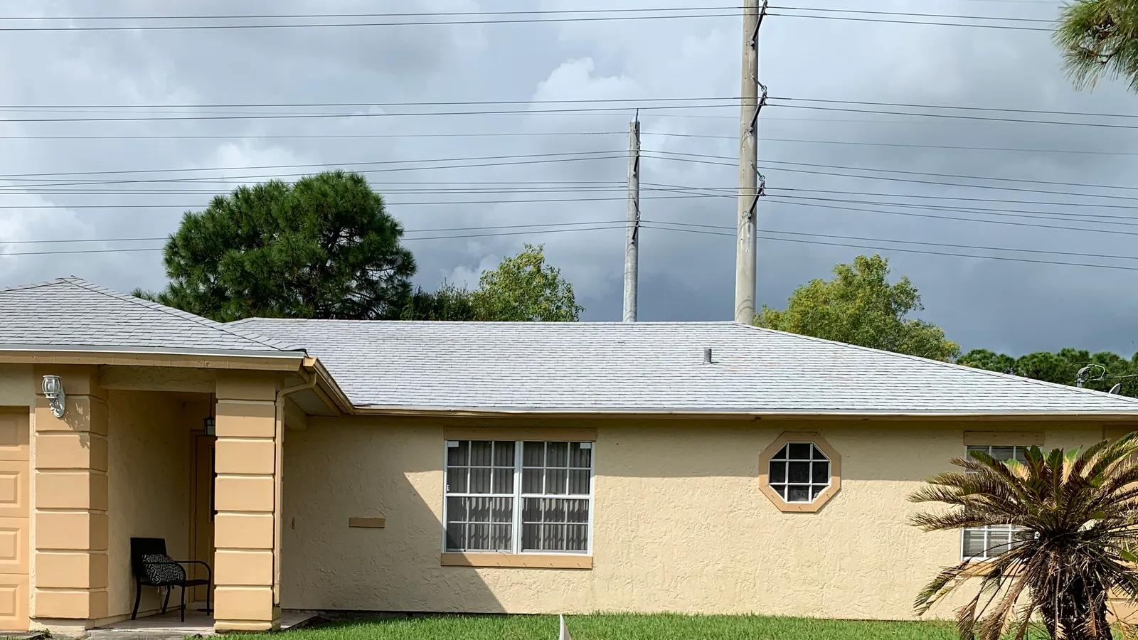Light gray shingle roof on a single-story stucco home beneath a cloudy sky.