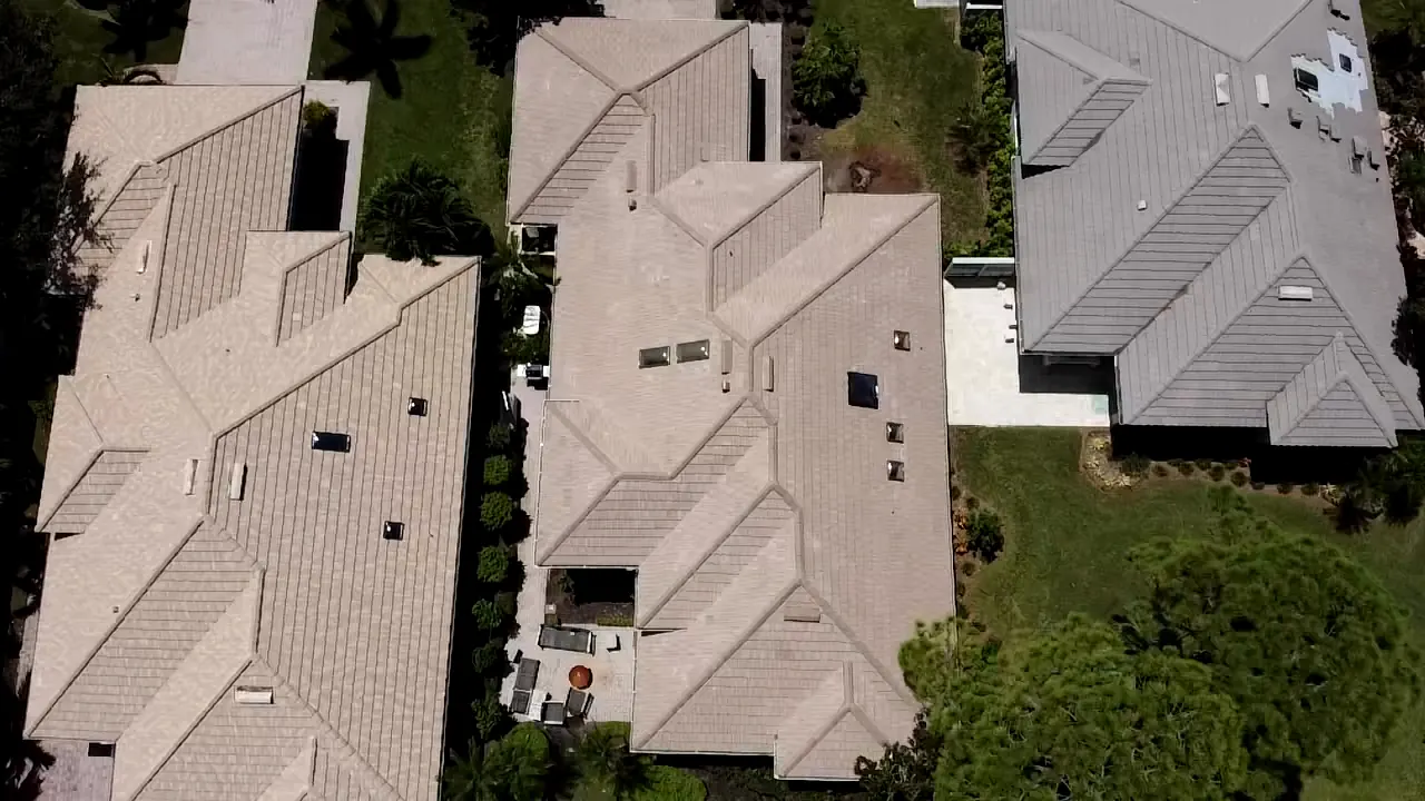 Top-down aerial view of neighboring homes with beige concrete tile roofs.