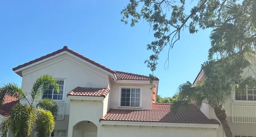 Roof-focused view of a two-story stucco home with a red barrel-style tile roof.