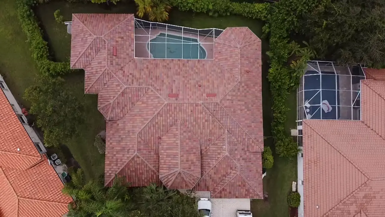Top-down aerial view of a completed red concrete tile roof beside a pool.