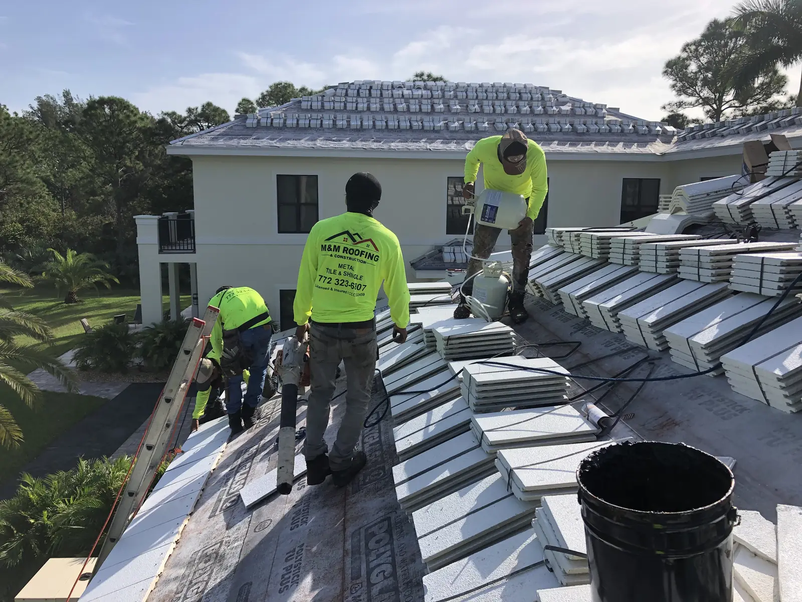M&M Roofing crew installing flat roof tiles on a two-story home.