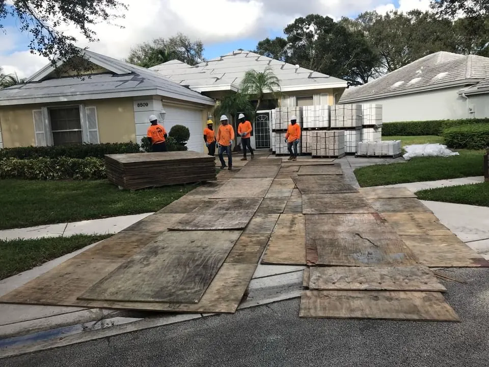 Roofing crew and materials staged on driveway protection at a home.