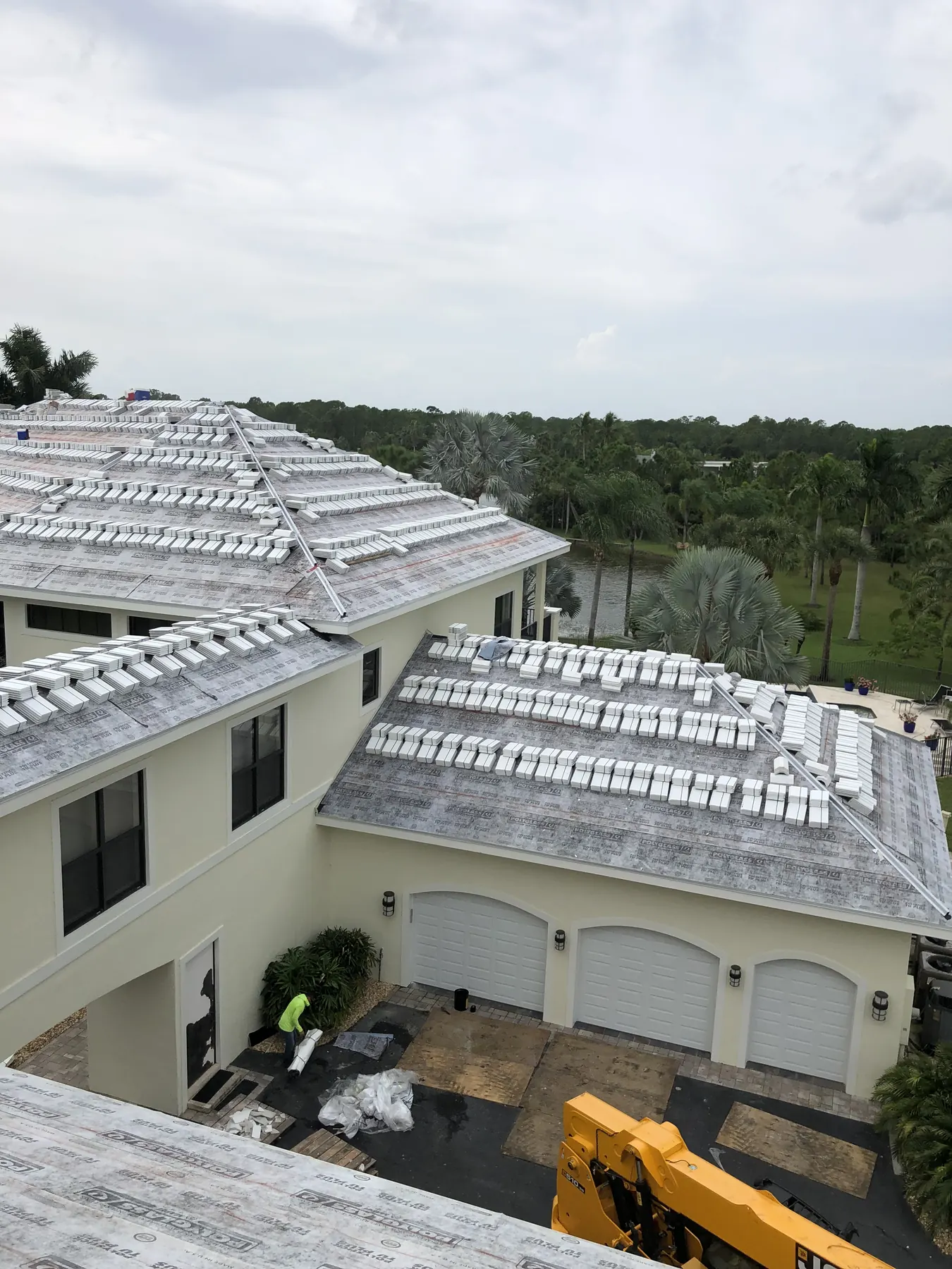 Elevated view of tile roof installation underway on a large two-story home.