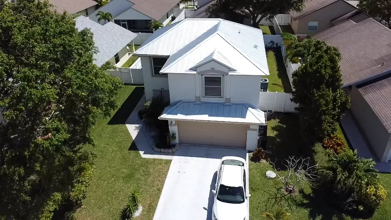 Elevated front view of a completed white metal roof and covered entry.
