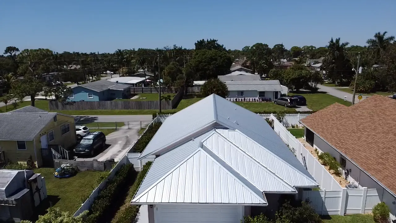 Rear aerial view of a compact two-story home with a completed white metal roof.