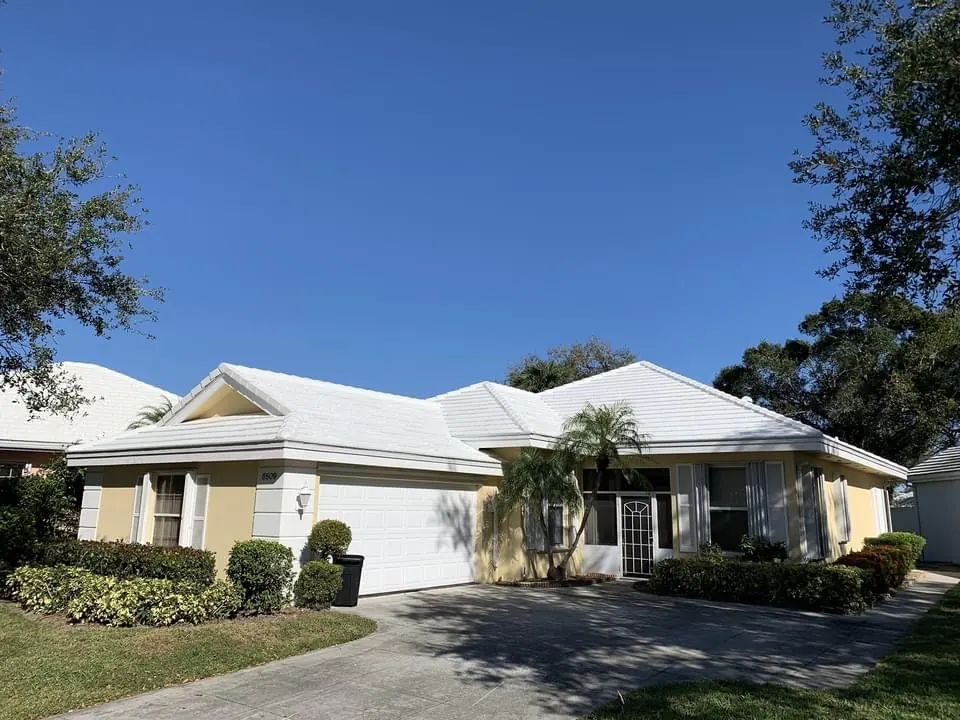 Street view of a single-story home with a completed white metal roof.
