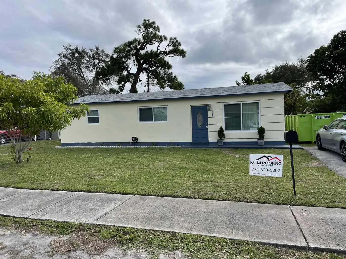 Single-story home with a completed white metal roof and an M&M Roofing yard sign.