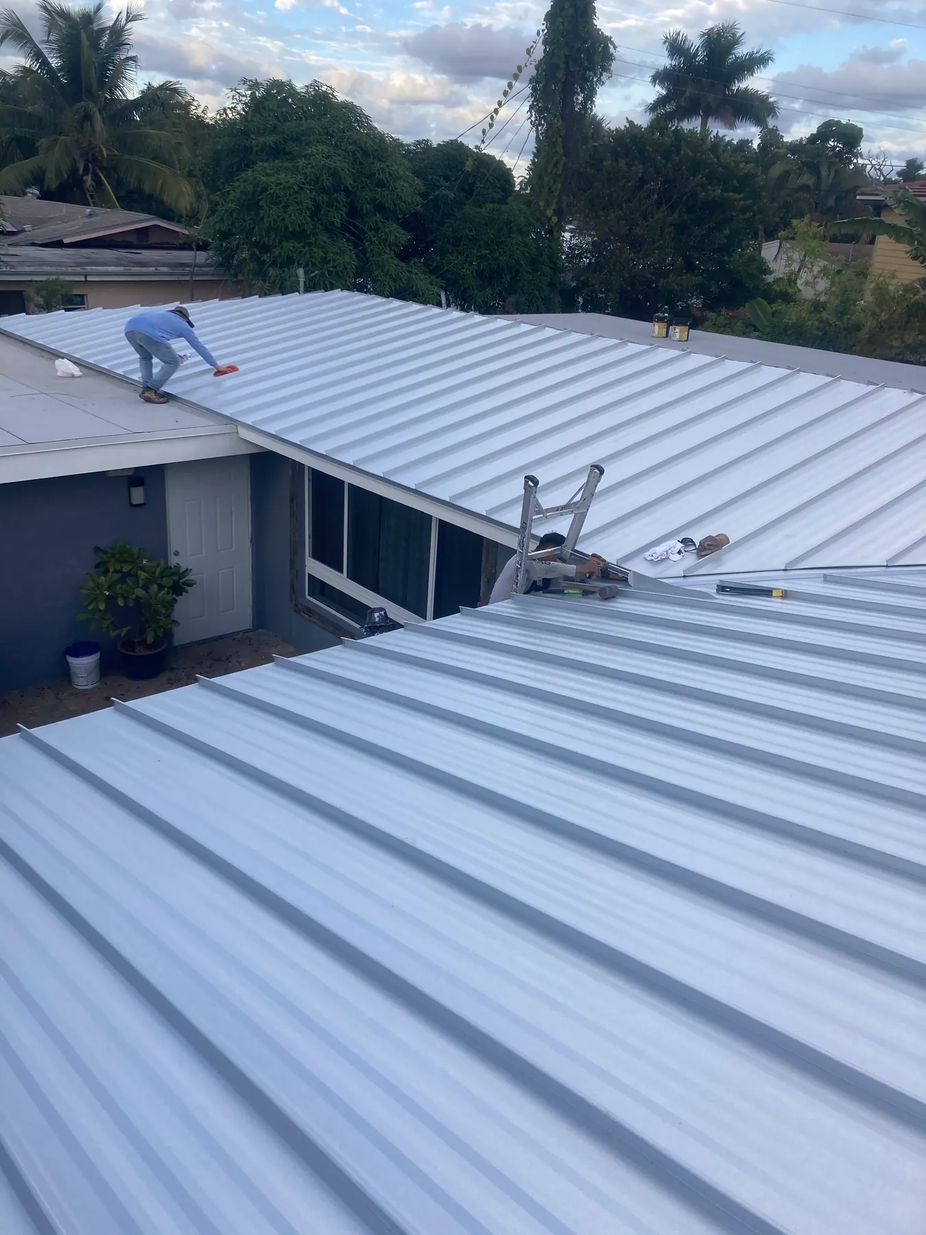 Close view of white standing-seam metal panels meeting at a ridge and valley.