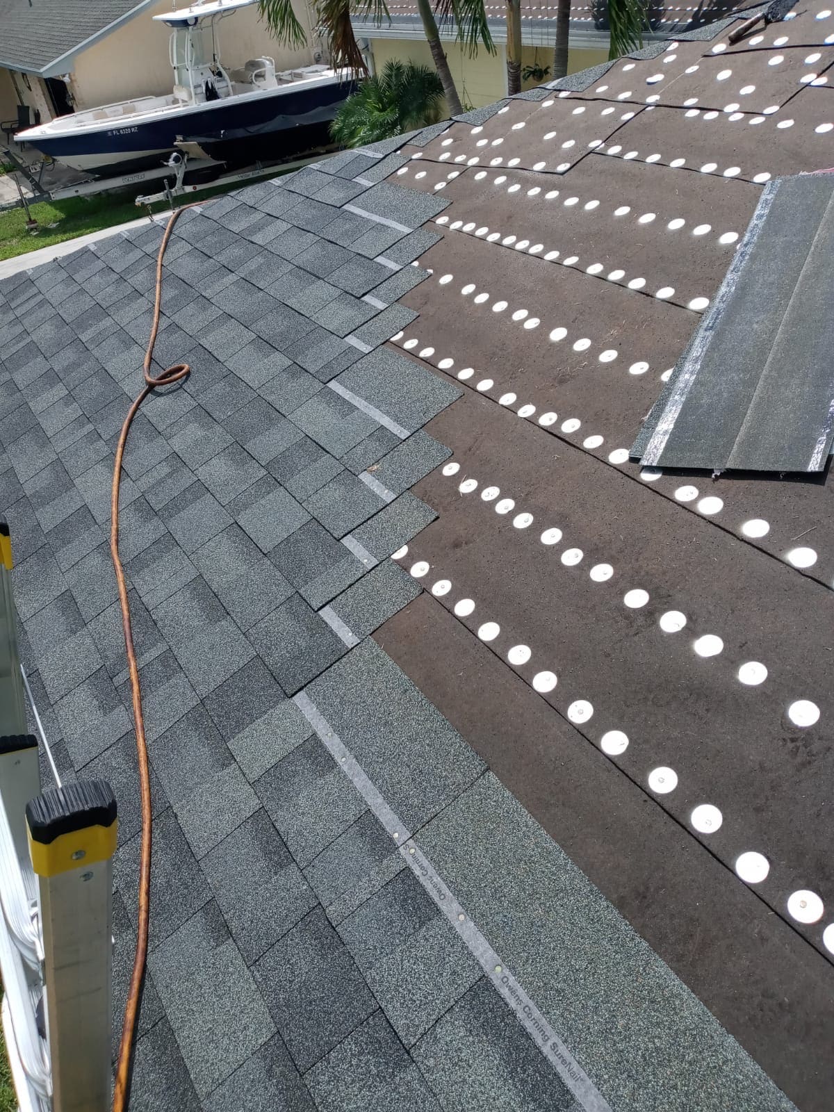 Gray asphalt shingles installed over lapped number 30 felt with tin-cap fasteners visible on the open roof deck.