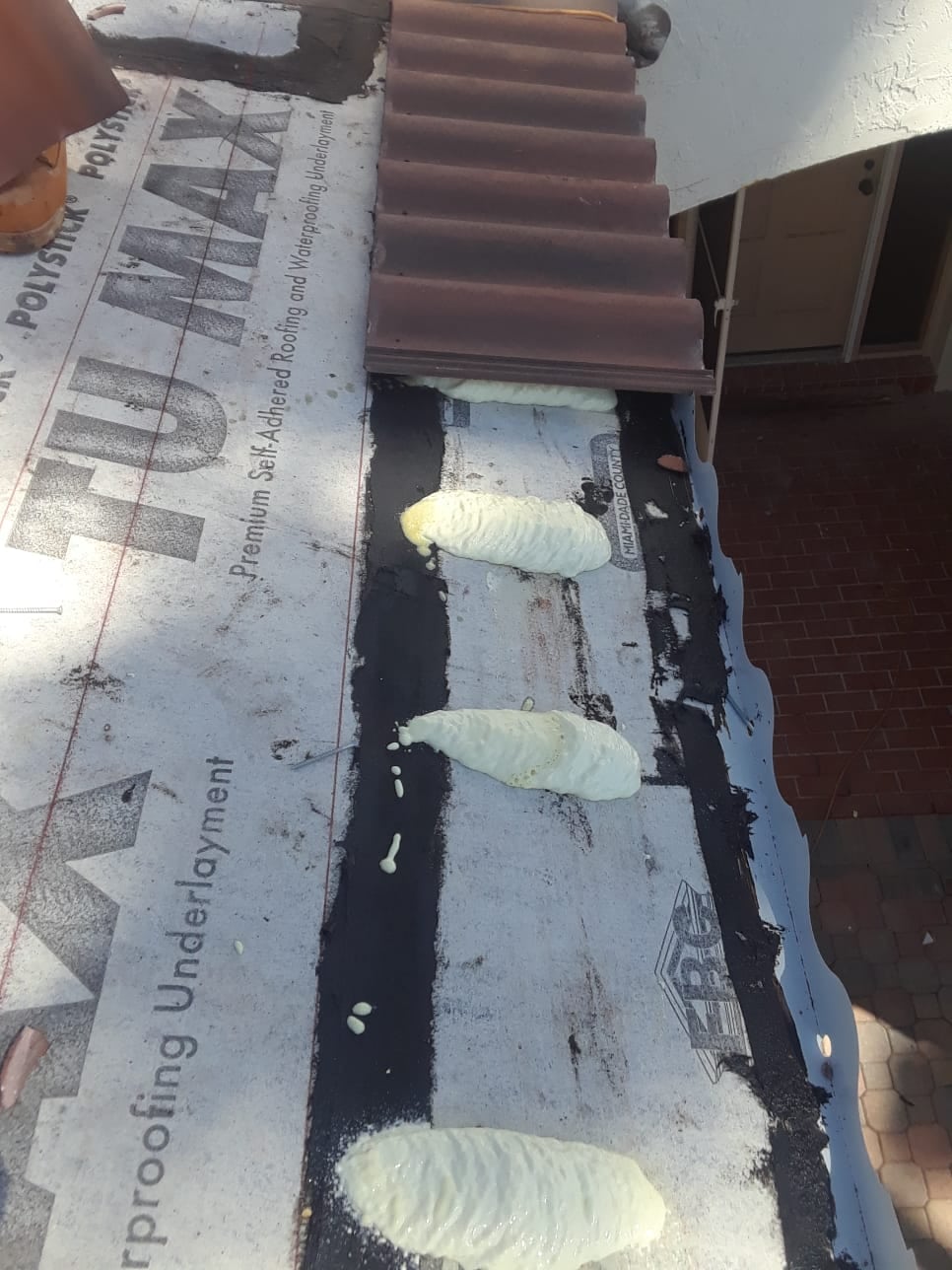 Roof tile adhesive patties on Polystick TU MAX underlayment beside a Villa 900 eave course on an M&M Roofing jobsite.