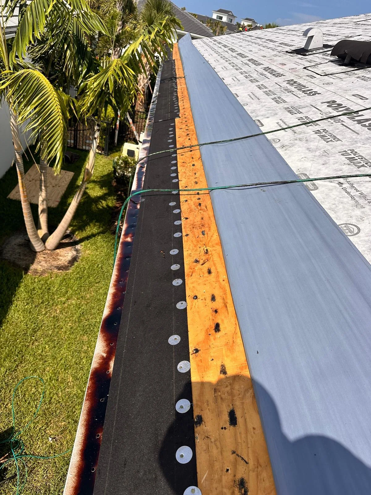 A long roof edge with Polystick TU MAX underlayment and a loose membrane roll during installation