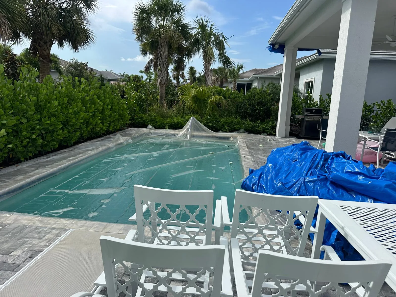 A covered swimming pool and protective tarps around the home during tile roof removal
