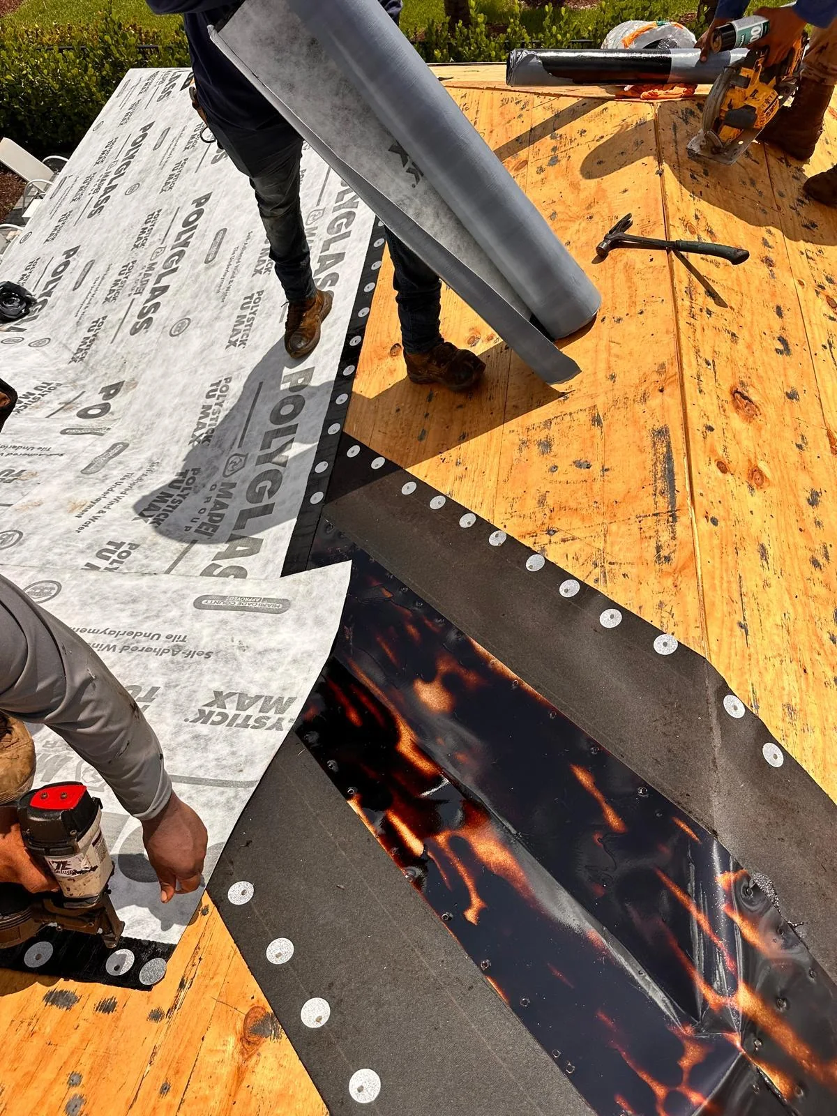 A roofer handling a roll of Polystick TU MAX at a prepared roof valley